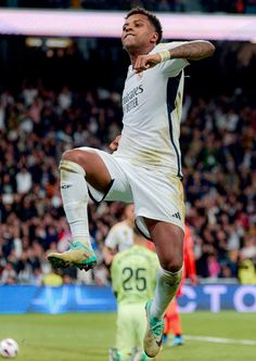 a man kicking a soccer ball on top of a field with people in the background