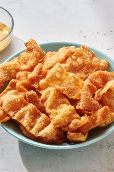 a blue bowl filled with fried food next to dipping sauce