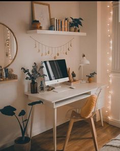 a white desk topped with a computer monitor next to a mirror and potted plants