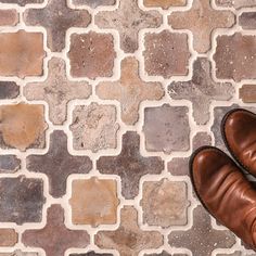 a pair of brown shoes sitting on top of a tiled floor