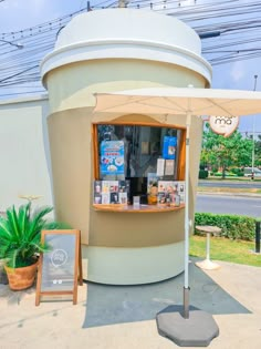 an outdoor kiosk with a sign and umbrella