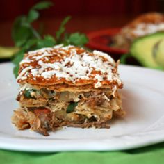 a white plate topped with layered lasagna next to an avocado