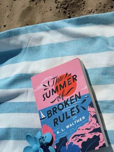 a book sitting on top of a blue and white striped blanket next to a flower