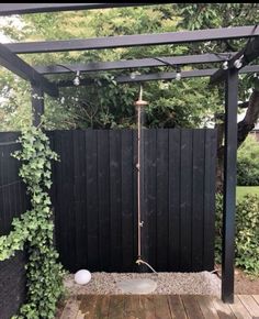 an outdoor shower in the middle of a wooden deck with plants growing on it's sides