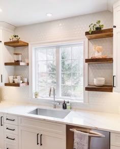 a kitchen with white cabinets and open shelving above the sink is seen in this image