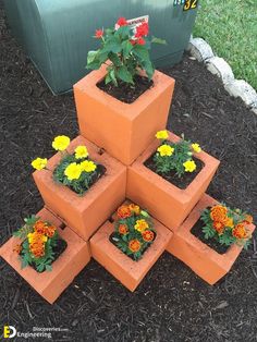 a stack of orange cinder blocks with flowers growing out of them