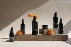 an assortment of skin care products arranged on a concrete stand with flowers in the background