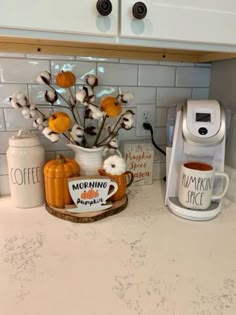 a coffee maker sitting on top of a counter next to a cup filled with flowers