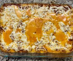 a casserole dish with cheese and meat in it on a granite countertop