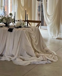 the table is covered with white cloths and flowers