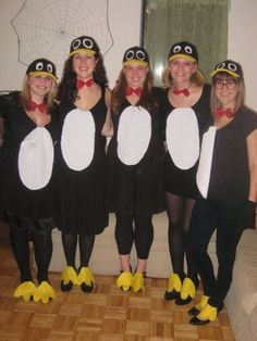 four women dressed in penguin costumes posing for a photo with one woman wearing yellow rubber shoes