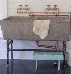 an old fashioned sink in the corner of a room with exposed pipes and piping