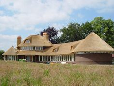 a large house with a thatched roof in the middle of a field