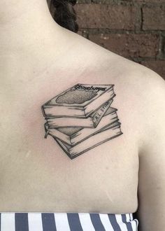 a woman with a tattoo on her chest has books stacked on top of each other