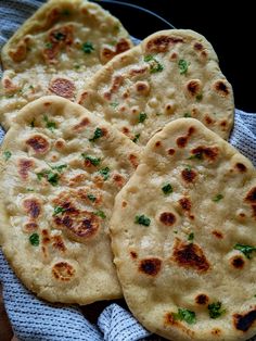 four pita breads on a blue towel with parsley sprinkled on them