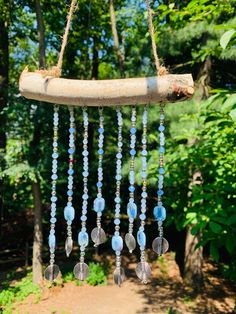 a wind chime hanging from a tree branch in the woods with blue beads on it