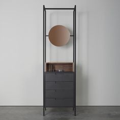 an empty room with a black cabinet and round mirror on the wall next to it