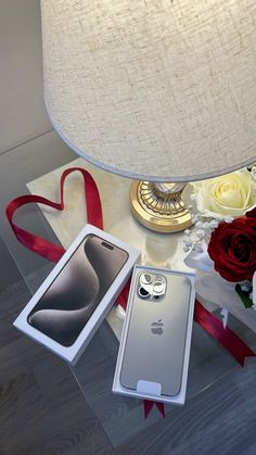 an iphone is sitting on a table next to flowers and a lamp with a red ribbon around it