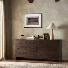 a wooden dresser sitting next to a lamp on top of a table in a room