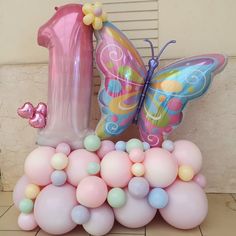 a pink and blue number one balloon sitting on top of balloons