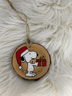 a wooden ornament with a cartoon dog holding a christmas present on it's side