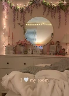 a bedroom with flowers and lights on the wall next to a mirror that says i love my room