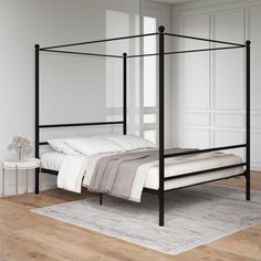 a black metal bed frame in a white room with hardwood floors and walls, along with a rug on the floor