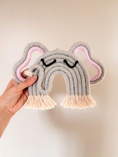 a hand holding up a gray and pink stuffed animal with horns on it's face