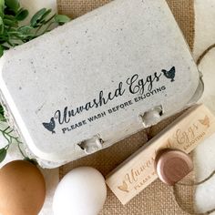 an egg carton sitting on top of a table next to eggs and two rubber stamps