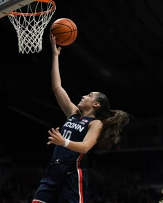 a women who is jumping up to dunk a basketball in the air with her right hand