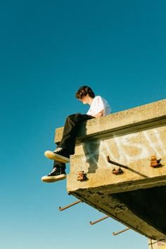 a man sitting on top of a cement structure with his feet up in the air