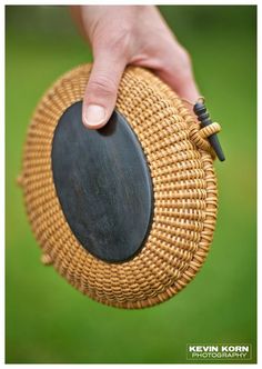 a person is holding a round basket with a small black disc on it's side