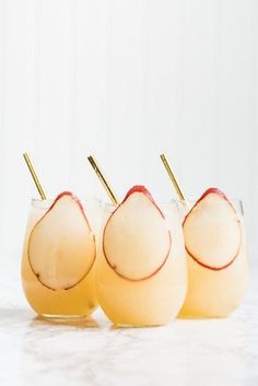 three glasses filled with drinks sitting on top of a white table next to each other