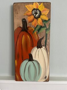 a painting of three pumpkins and a sunflower