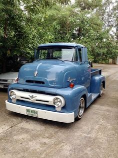 an old blue truck parked in a parking lot