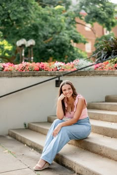 a woman is sitting on the steps talking on her cell phone and smiling at the camera