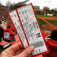 someone holding up two tickets at a baseball game