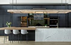 a kitchen with marble counter tops and stools next to an island in the middle