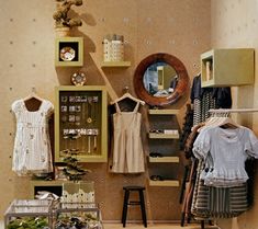 a room filled with lots of clothes on display next to a wall mounted mirror and shelf