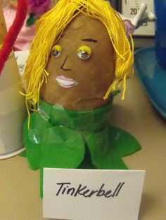 a fake potato head sitting on top of a desk next to a sign that says tinkerbell