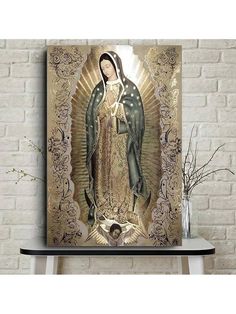 an image of the virgin mary in gold and black on a white brick wall above a shelf