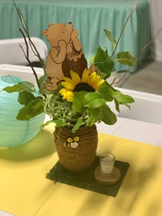 a vase with sunflowers and greenery on a table at a baby's first birthday party