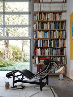 a chair sitting in front of a bookshelf filled with lots of book shelves