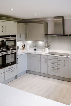 an empty kitchen with white cabinets and light wood flooring on the counter top,