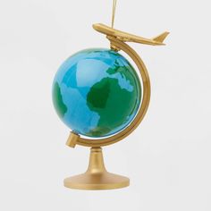 an ornament shaped like a globe with a plane flying over it on a white background