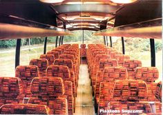 an empty bus filled with lots of seats next to grass and trees in the background