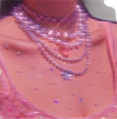 a woman in a pink dress with pearls on her neck and necklaces around her neck