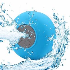 a blue water - resistant speaker floating in the air with splashing water around it