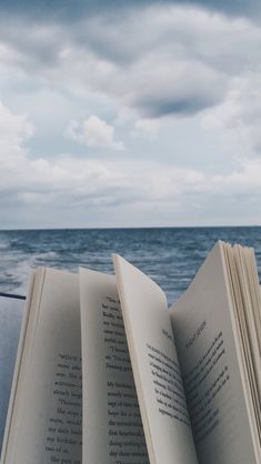 an open book sitting on top of a table next to the ocean