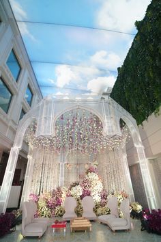 an outdoor wedding setup with flowers and chandeliers on the ceiling, surrounded by greenery